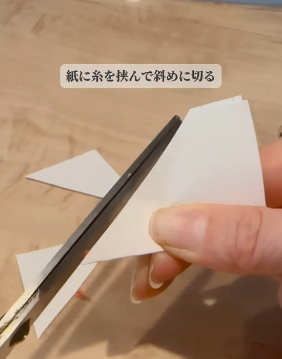 紙と糸をハサミで切っている様子