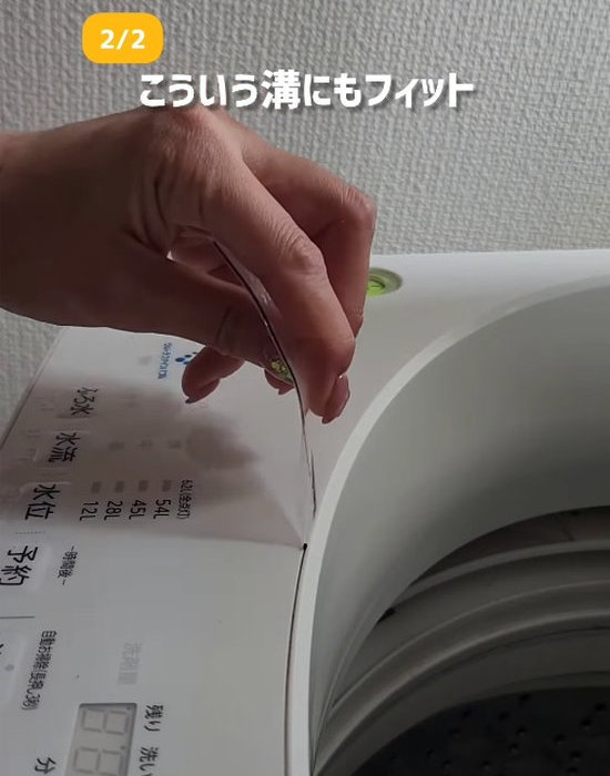 三角形に切ったクリアファイルの角で洗濯機の溝を掃除している様子