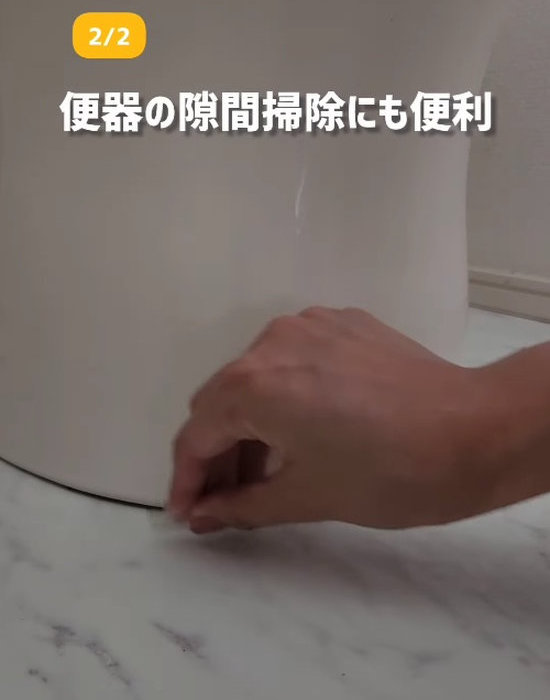 三角形に切ったクリアファイルの角で便器の隙間を掃除している様子