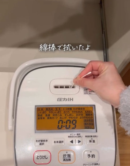 炊飯器の細かい部分を綿棒で掃除している画像
