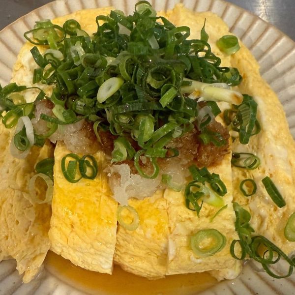完成した『だし巻き卵』に大根おろしとネギをのせて醤油をかけた様子