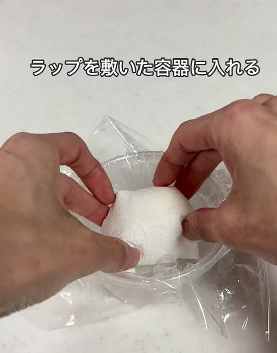 キッチンペーパーで包んだゆで卵をラップの敷いた容器に入れる様子