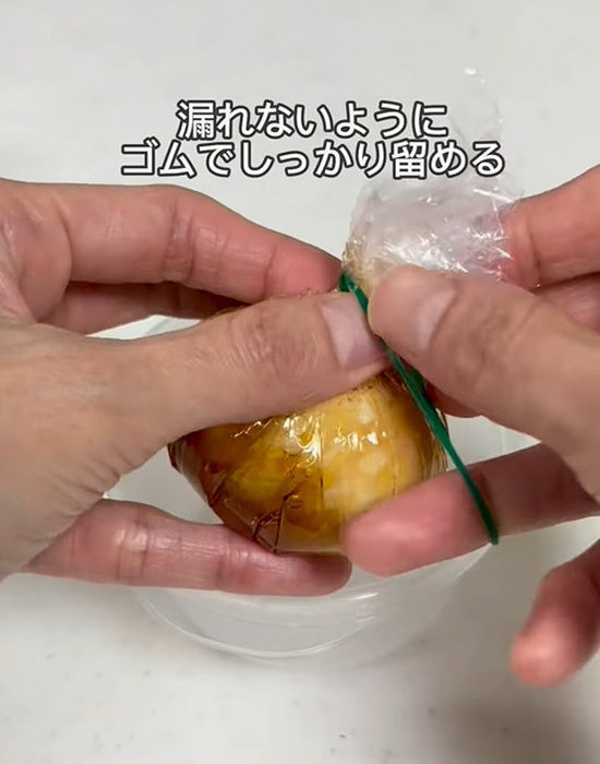 ラップ包んだゆで卵を輪ゴムで留める様子