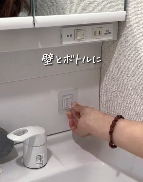 差し込み型シールフックを洗面所の壁面に貼る様子