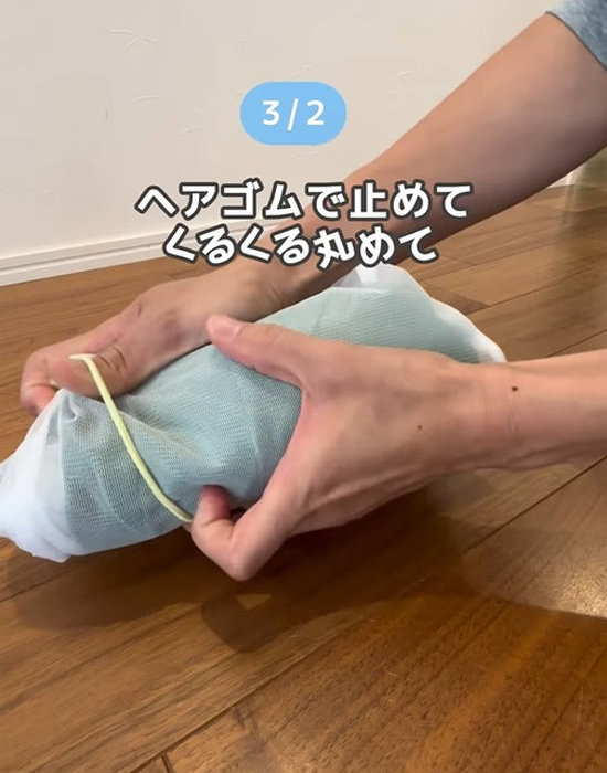 丸めた衣類の入った洗濯ネットをヘアゴムで固定する様子