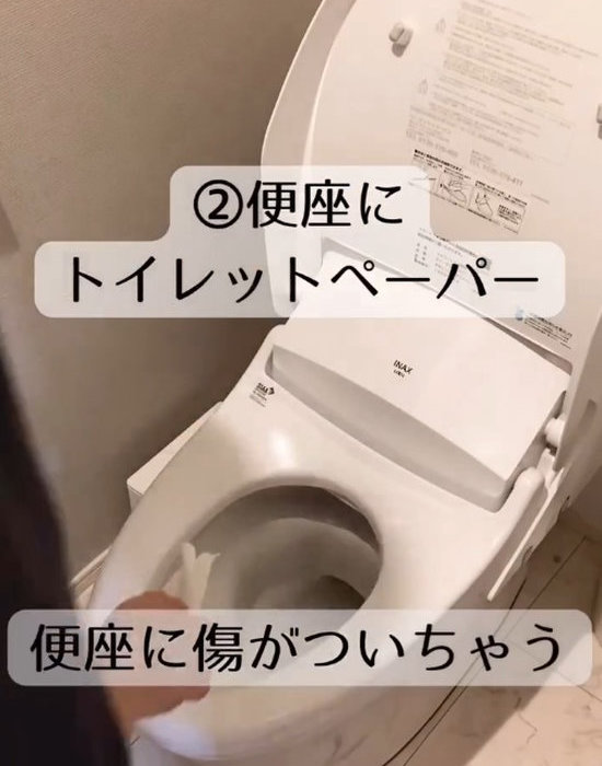 トイレの便座をトイレットペーパーで拭く様子