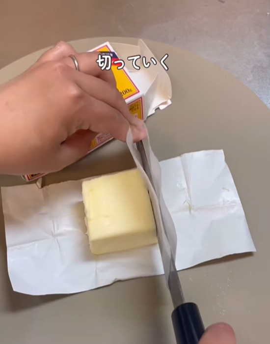 クッキングシートを巻いた包丁でバターを切る様子