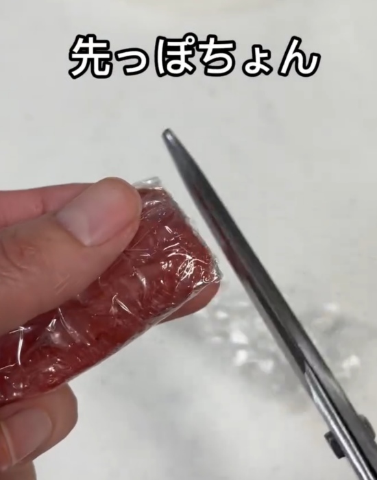 ラップで包んだ明太子の先をハサミで切っている様子