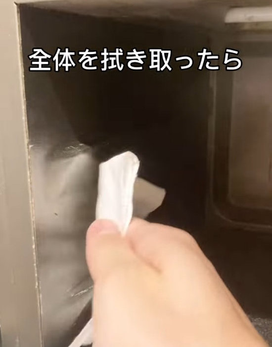 キッチンペーパーで電子レンジを拭く様子