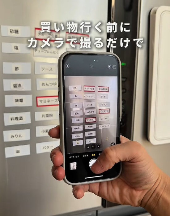 冷蔵庫に貼られたマグネットをスマートフォンのカメラで撮影する様子