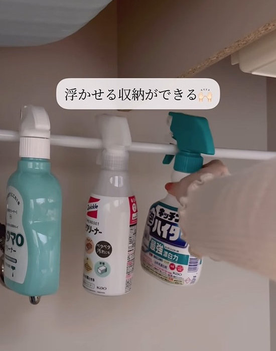 突っ張り棒に掃除用スプレーボトルを引っ掛ける様子