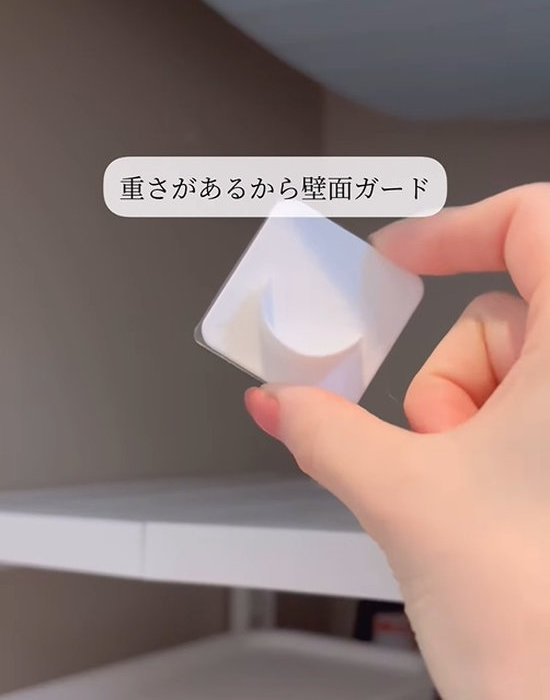 突っ張り棒用の壁面ガードを手にしている様子