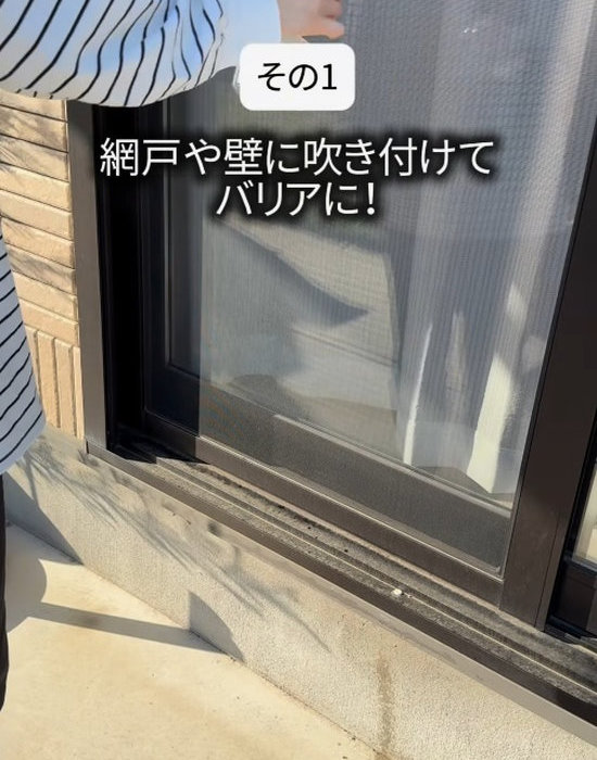 虫除けスプレーを網戸に吹きかけている様子