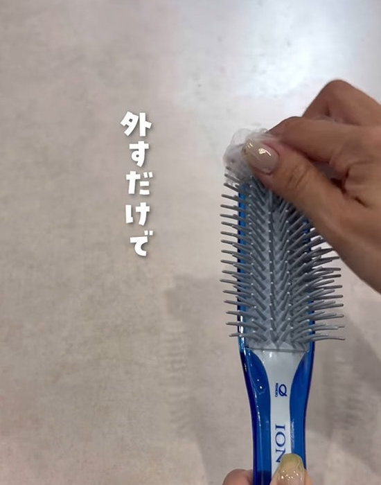 ヘアブラシに取り付けた排水口ネットを外している様子
