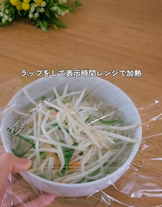 乾麺と野菜の入ったどんぶりにラップをかける様子