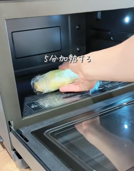 ラップしたトウモロコシを電子レンジに入れる様子