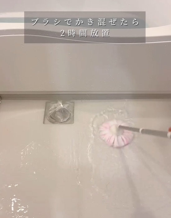 ブラシで浴室の床掃除をしている様子