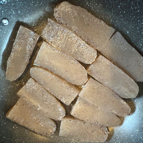 切った板こんにゃくをフライパンに並べて焼く様子