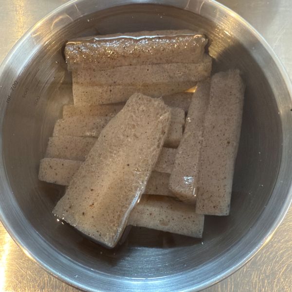 カットした板こんにゃくを酢水の入ったボウルに入れた様子