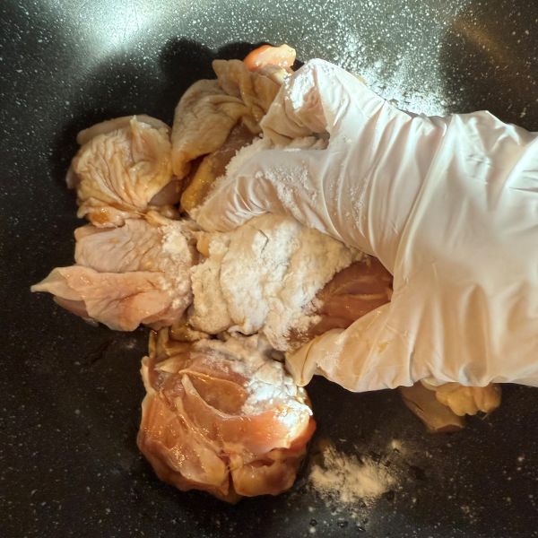 調味料をもみ込んだ鶏肉に片栗粉をまぶしてもみ込む様子