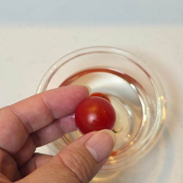 お湯に漬けていたミニトマトを指で触る様子