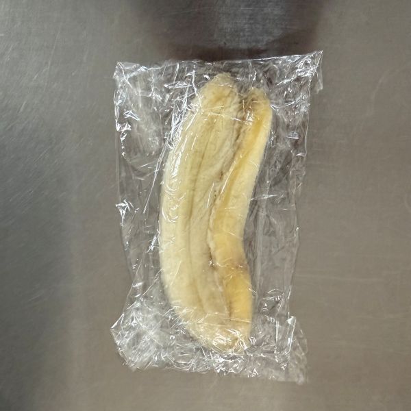 手のひらでラップに包んだバナナをつぶした状態の写真
