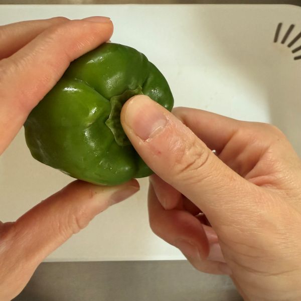 ピーマンのヘタ部分を親指で中に押し込む様子