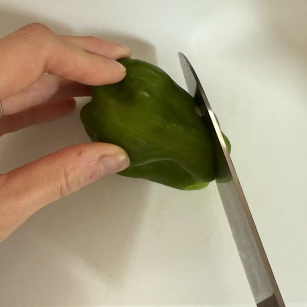 ピーマンのおしりの部分に斜めに包丁を入れる様子