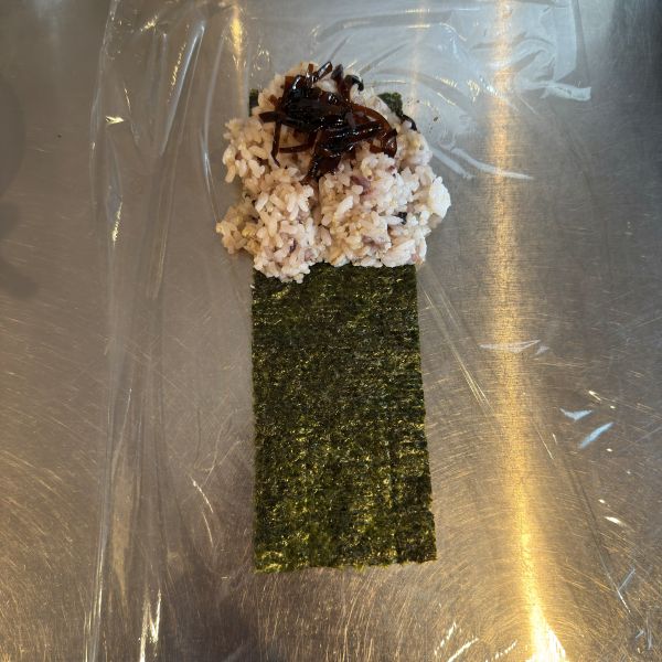 ラップの上に置いたのりの上にご飯と昆布を置いた様子