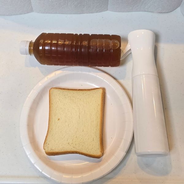 紙皿にのせた食パンとスプレーボトルとペットボトルに入った麦茶を並べた写真