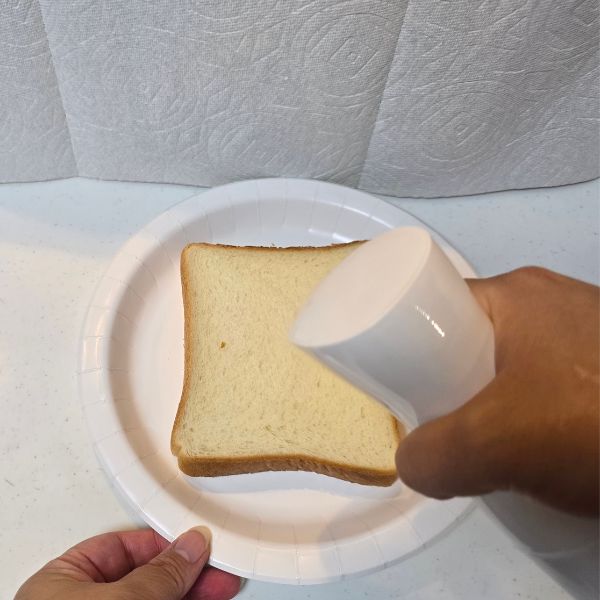スプレーボトルに入れた麦茶を食パンにかける様子