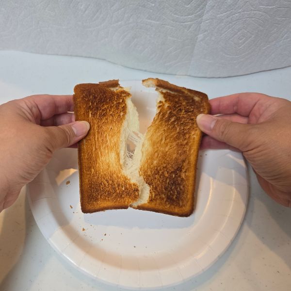 こんがり焼けた食パンを両手で端を持って割く様子