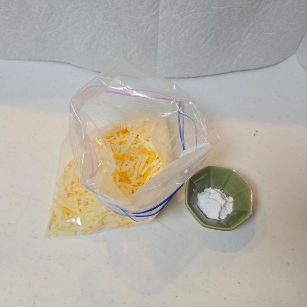 ピザ用チーズを入れた冷凍用保存袋と小皿に入れた片栗粉を並べた写真