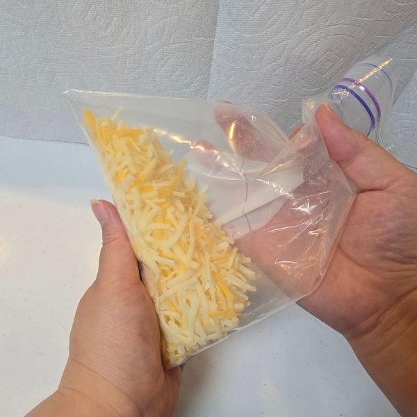 冷凍用保存袋に入れたピザ用チーズと片栗粉を混ぜ合わせる様子