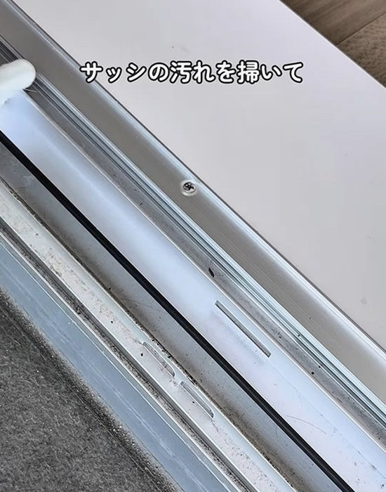 サッシの汚れを掃く様子