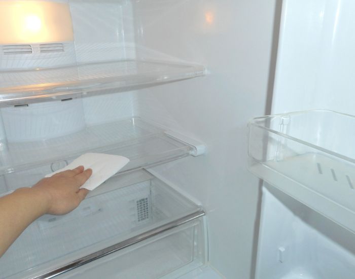 空っぽの冷蔵庫を拭き掃除する様子