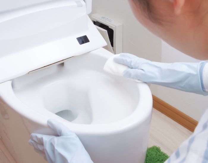 ゴム手袋を着けて便器を拭く様子