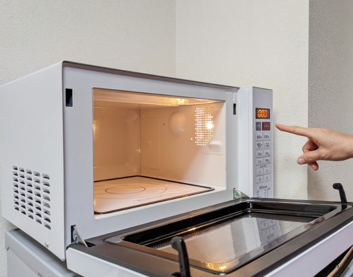 電子レンジの扉を開けてボタンを押そうとしている様子