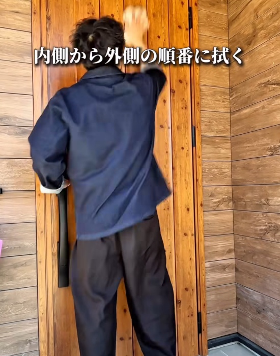 玄関ドアの外側を掃除している人