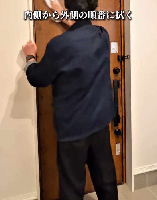 玄関ドアの内側を掃除している人