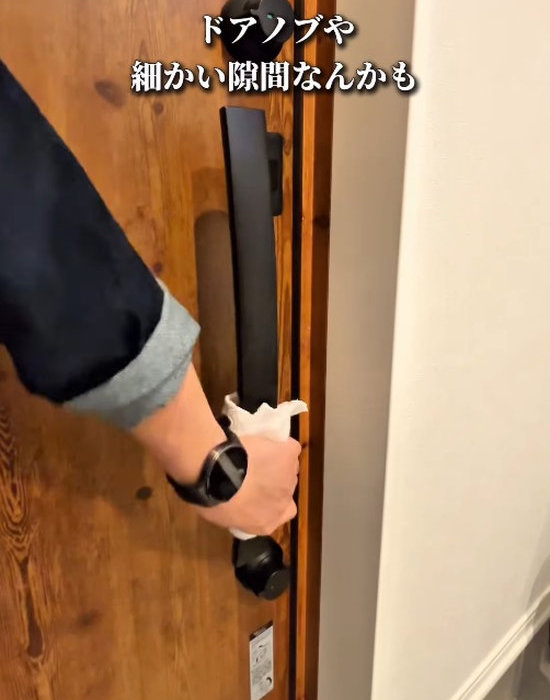 玄関のドアノブを掃除している人