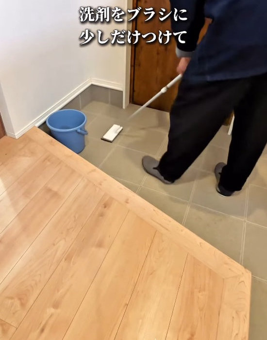 玄関の床をブラシで掃除している様子