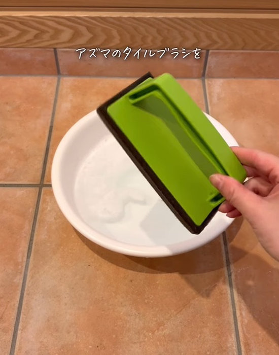 玄関タイルブラシスポンジを手にしている様子