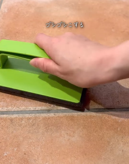 玄関のタイルをブラシでこする様子