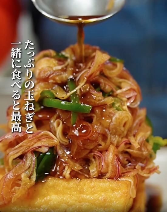 厚揚げの上に野菜とタレをかける様子