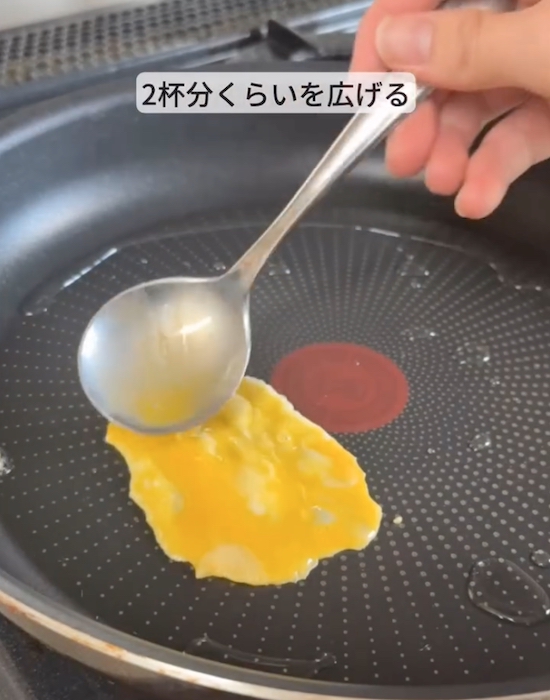 フライパンに卵を広げ入れる様子