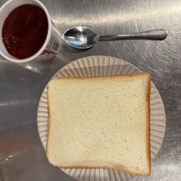 皿にのせた食パンとスプーンといちごジャムを並べた写真