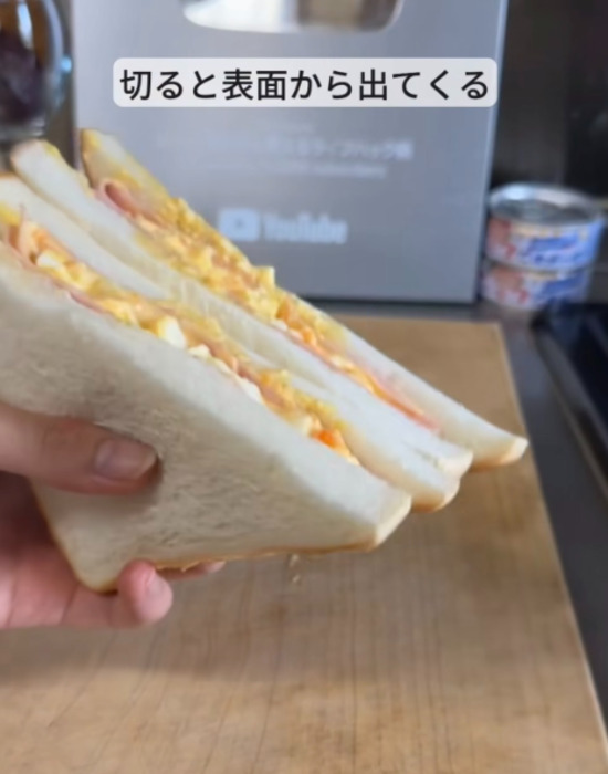 カットしたハムたまごサンドを手にしている様子