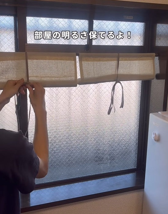窓に設置したロールスクリーンを巻く様子