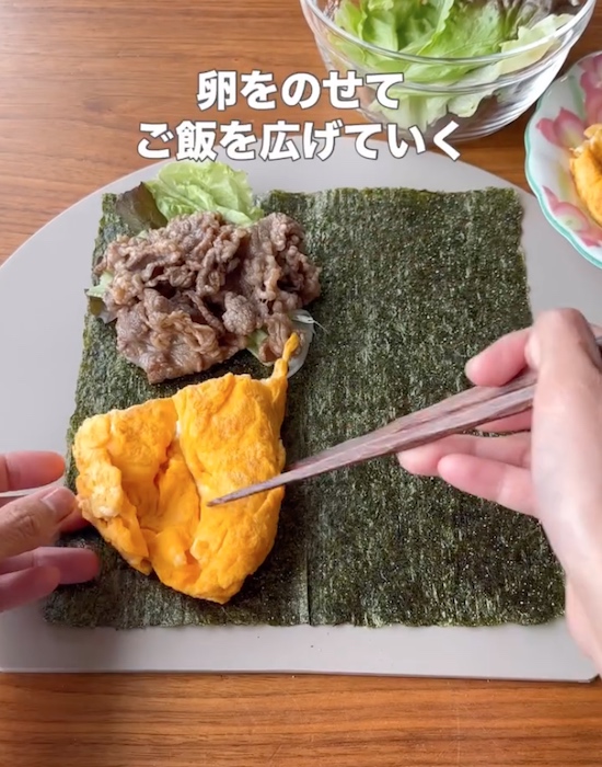 海苔の上にレタスと牛肉と卵をのせる様子